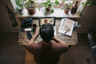 Directly above shot of businessman on video call through laptop with male colleague at home office