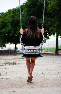 Rear view of woman sitting on swing at playground