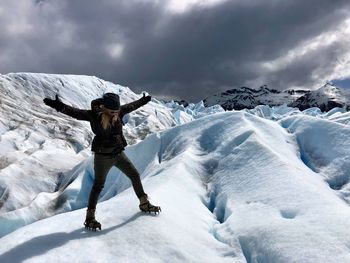 Woman with arms outstretched standing against snowcapped mountains 