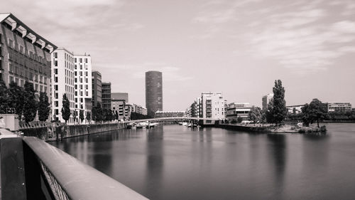 River by buildings in city against sky