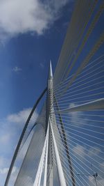 Low angle view of suspension bridge against cloudy sky