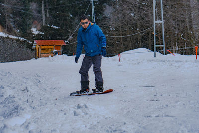 Full length of man snowboarding over snow covered land