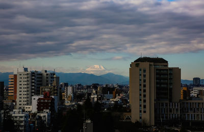 Buildings in city against cloudy sky