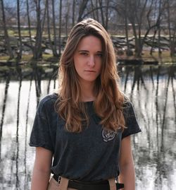 Portrait of beautiful young woman standing against lake