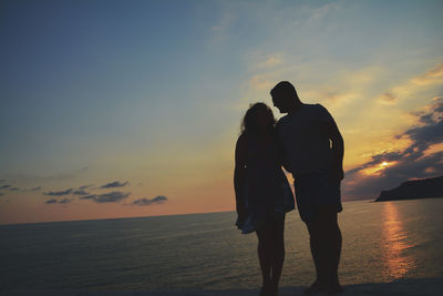 Silhouette couple on beach against sky during sunset