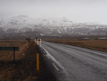 Road by snowcapped mountains against sky