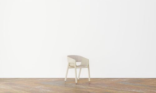 Empty chair against white wall