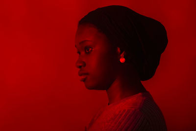 Young woman contemplating in front of red background