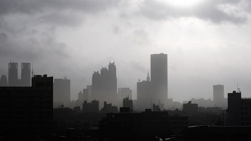 View of cityscape against cloudy sky