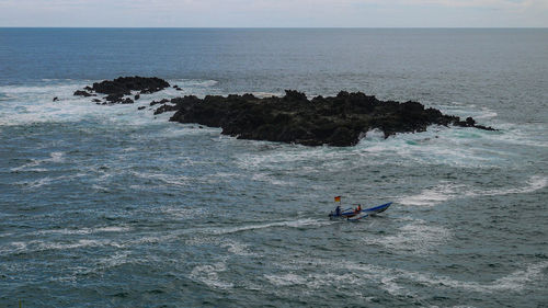 Small coral rock island in the ocean with traditional ship sailling view from menganti beach