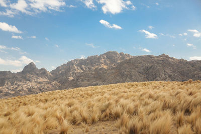 Scenic view of landscape against sky, rock mountains at background.