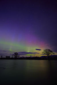 Aurora polaris lighting up the sky over the madison river and reflecting off the water