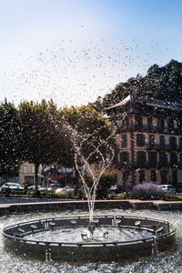 Fountain in park against sky in city