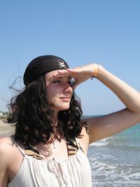 Young woman standing by sea against clear sky