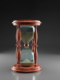 Close-up of hourglass on table against black background