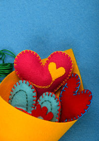 Close-up of heart shape decorations in yellow fabric against blue floor