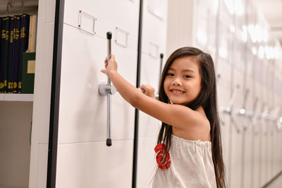 Portrait of smiling girl opening locker