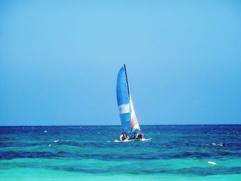 People sailing on sea against clear sky