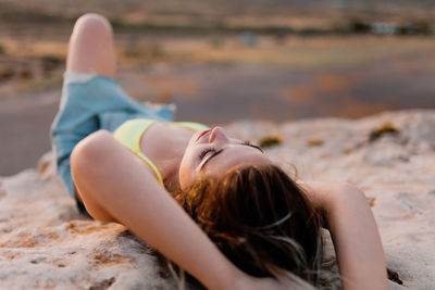 Woman lying on beach against sky