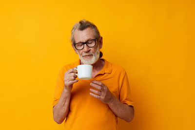 Portrait of young woman drinking milk against yellow background