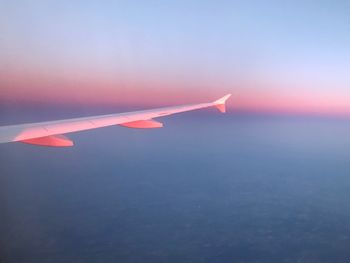 Airplane flying in sky at sunset