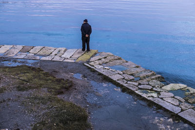 Rear view of man standing by sea