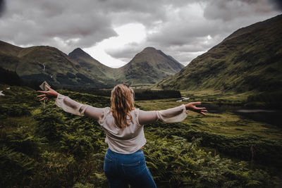 Rear view of man with arms raised against mountains