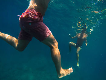 Low section of men swimming in sea