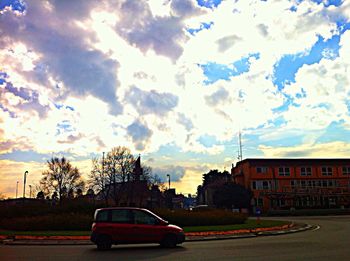 Cars parked on road against cloudy sky