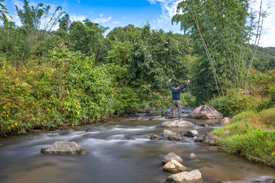 Man standing by river in forest