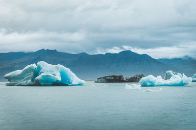 Scenic view of glaciers in sea against mountains