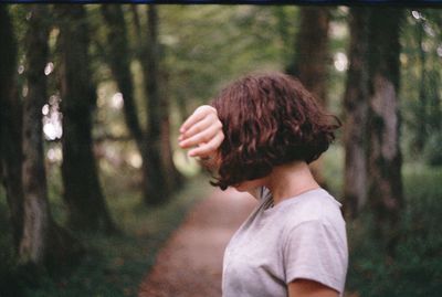 Side view of woman against trees in forest