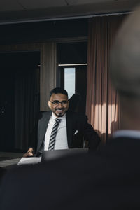 Smiling businessman looking at male colleague in board room during meeting