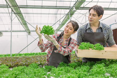 Portrait of smiling friends standing by plants