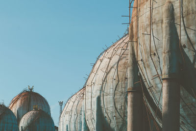 Panoramic shot of tanks against clear blue sky