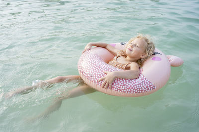 Girl with inflatable ring floating on sea