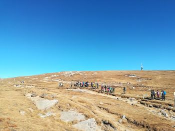 People on landscape against clear blue sky