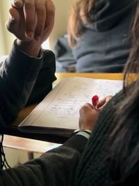 Cropped of person writing in book on table 