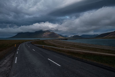 Road leading towards mountains against sky