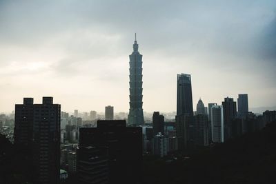 Skyscrapers in city against cloudy sky