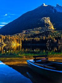 Scenic view of lake by mountains against blue sky