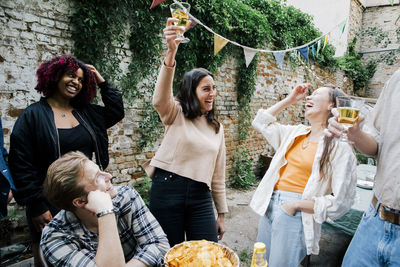 Cheerful woman celebrating with male and female friends at dinner party in back yard