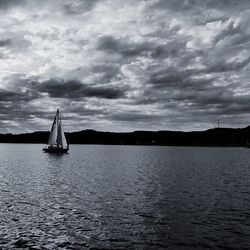 Sailboat sailing on sea against dramatic sky