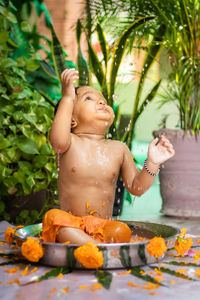 Cute toddler baby boy bathing in decorated bathtub at outdoor from unique perspective