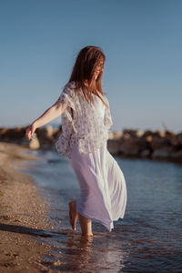 Rear view of woman with arms raised against clear sky