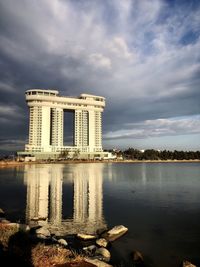 Reflection of building in lake against cloudy sky