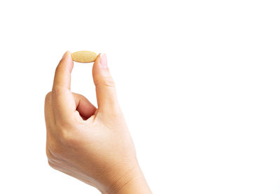 Close-up of woman hand holding ring against white background
