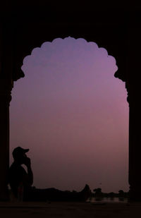 Side view of silhouette woman standing against sky during sunset