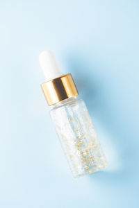 Bottle of 24k gold serum on a blue background. the concept of skin care at home