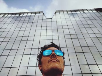 Low angle view of man wearing sunglasses against building